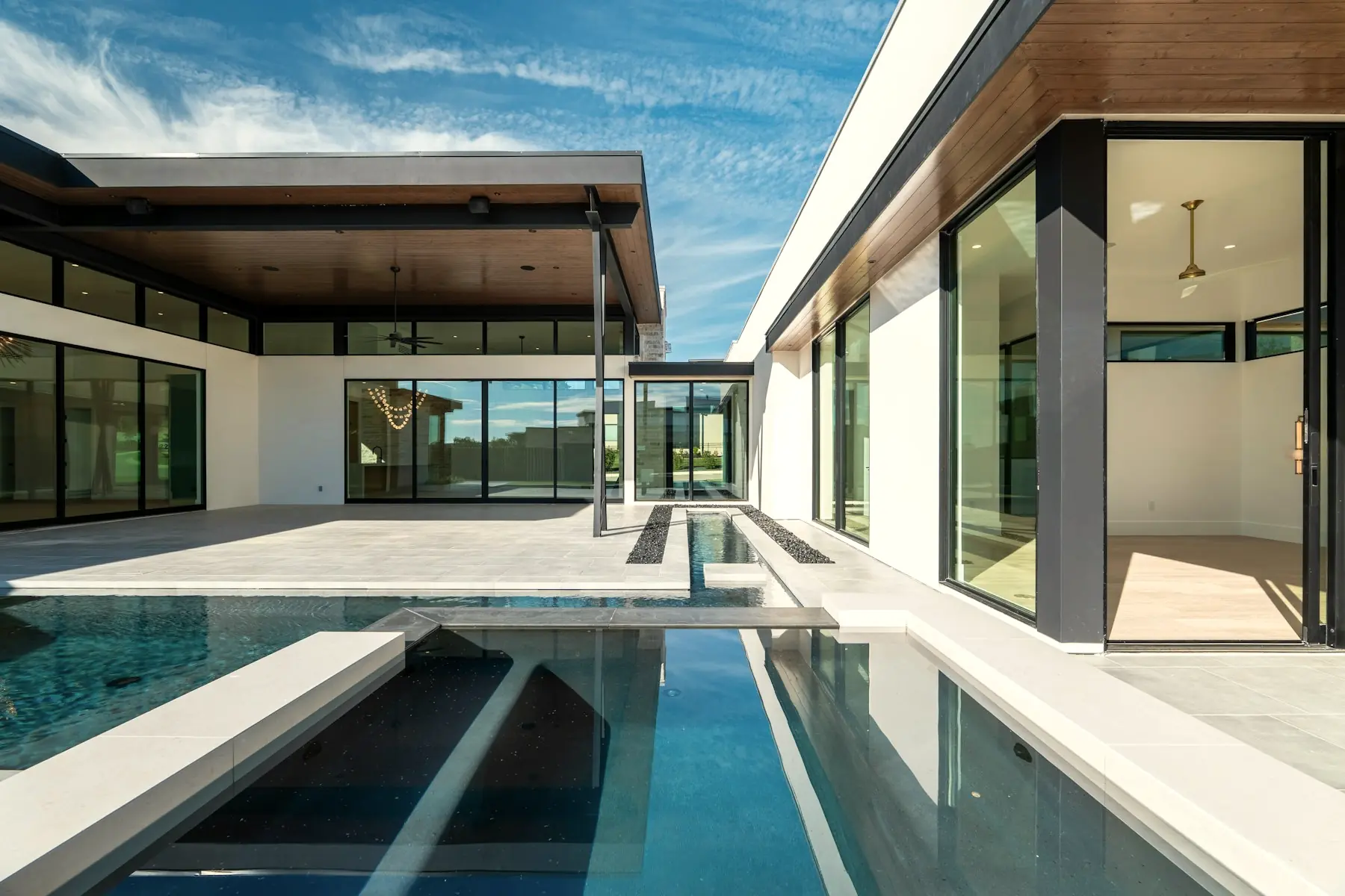 A modern limestone residence with a reflecting pool held between two glazed wings.