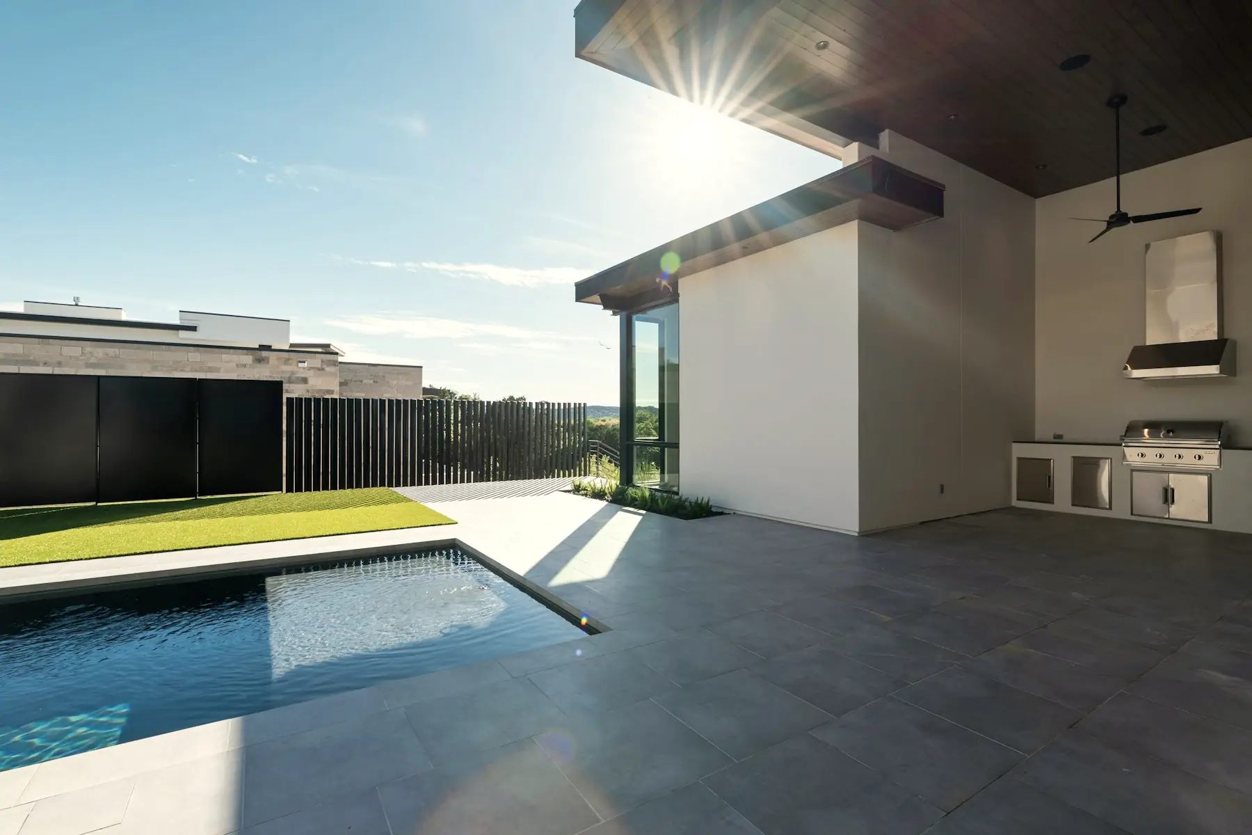 The courtyard at Caliza: a lap pool and two shallow reflecting channels set into limestone paving, with an outdoor kitchen under the roof.