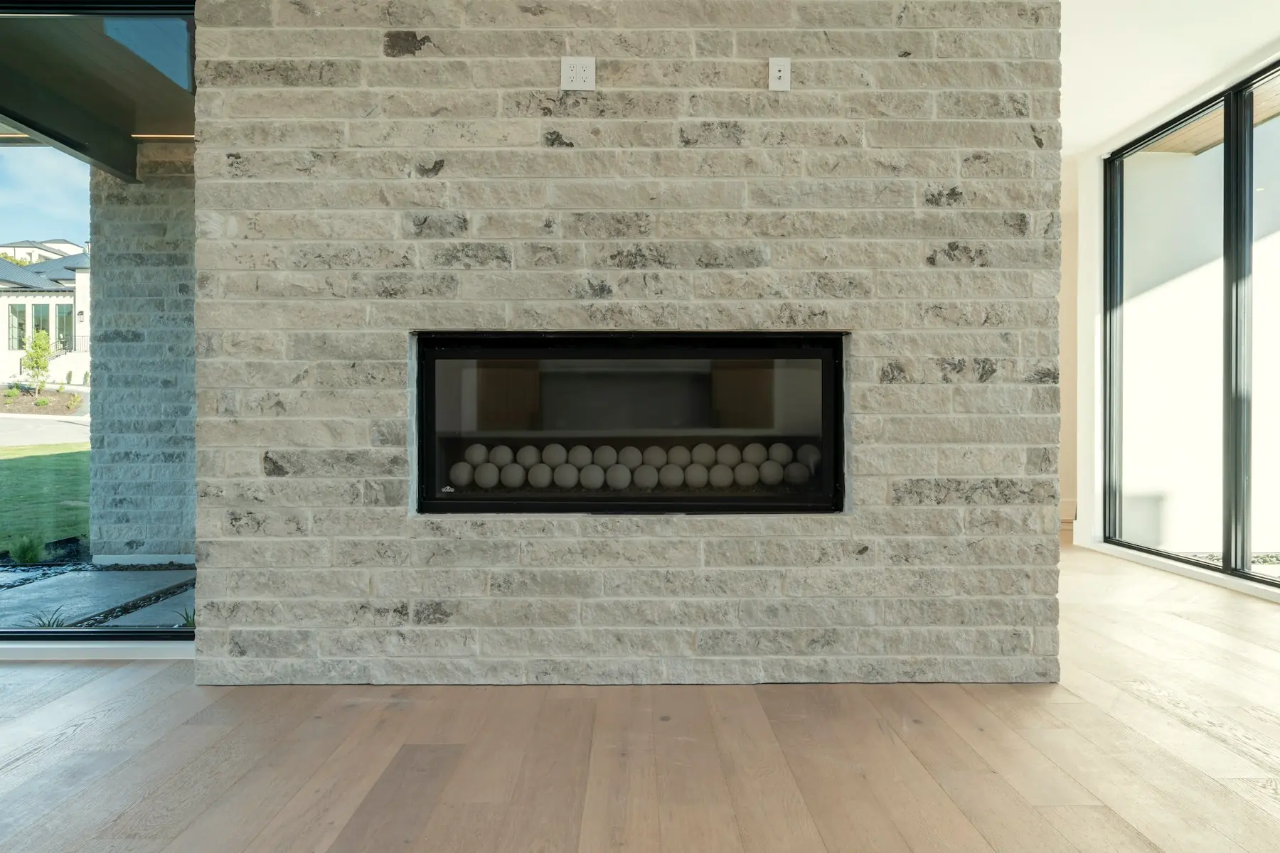 A limestone chimney wall running floor to ceiling, with a long horizontal firebox set into it.