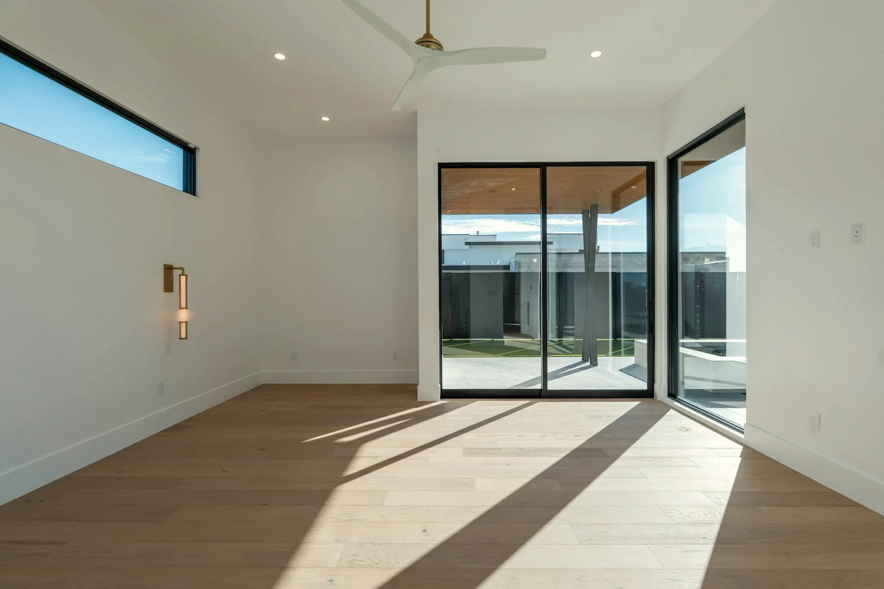 Afternoon light falling in long bands across a white oak floor beside full-height glazing.